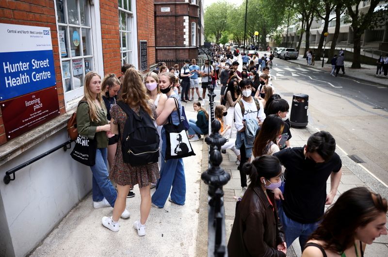 FILE PHOTO: People queue outside a vaccination centre for young