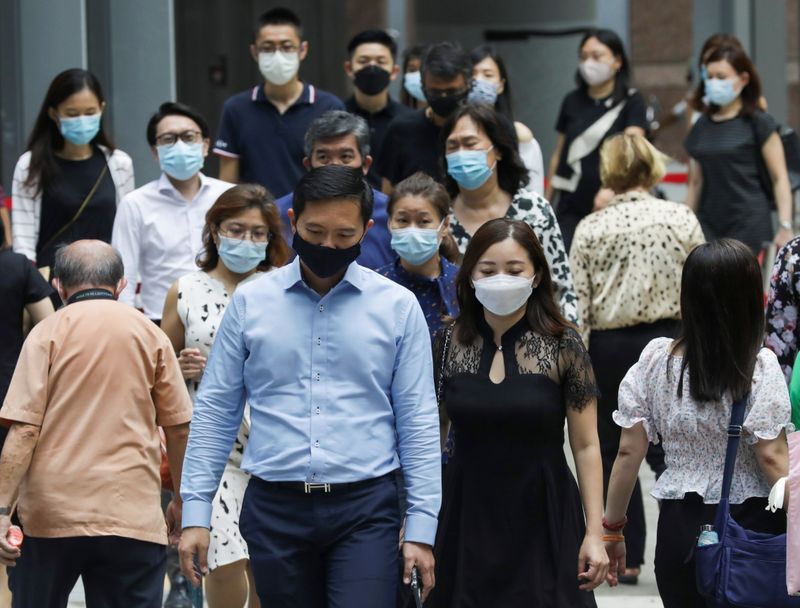 Office workers wearing masks cross a street during lunch hour,