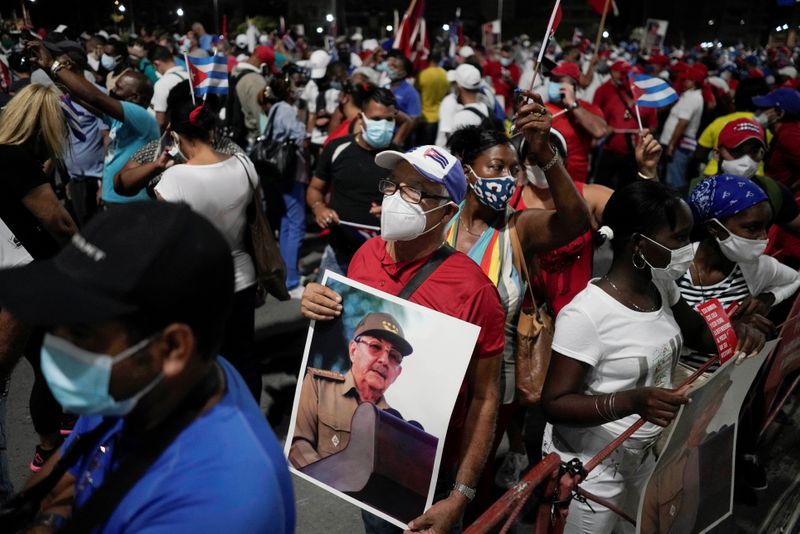A man holds an image of Raul Castro durig a