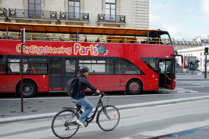 FILE PHOTO: A cyclist rides past an empty tourist bus