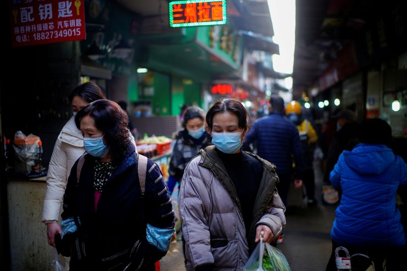 FILE PHOTO: People wearing face masks walk on a street