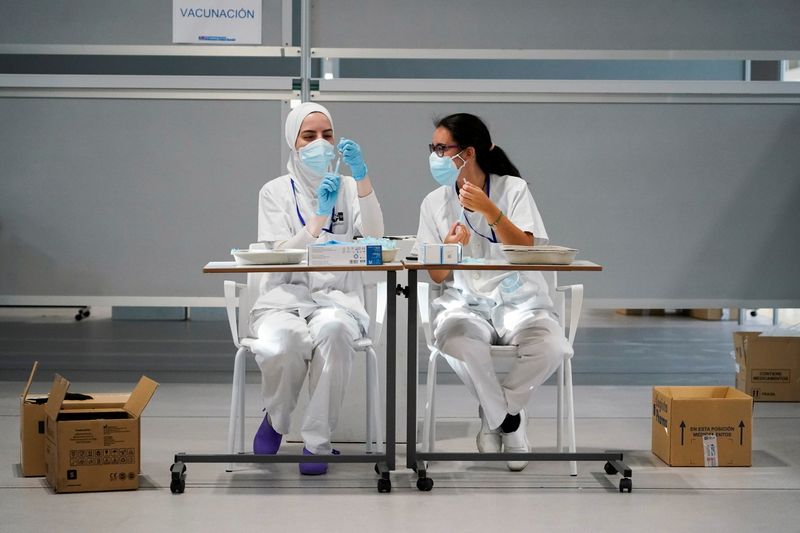 Nurses prepare syringes with doses of the Moderna coronavirus disease