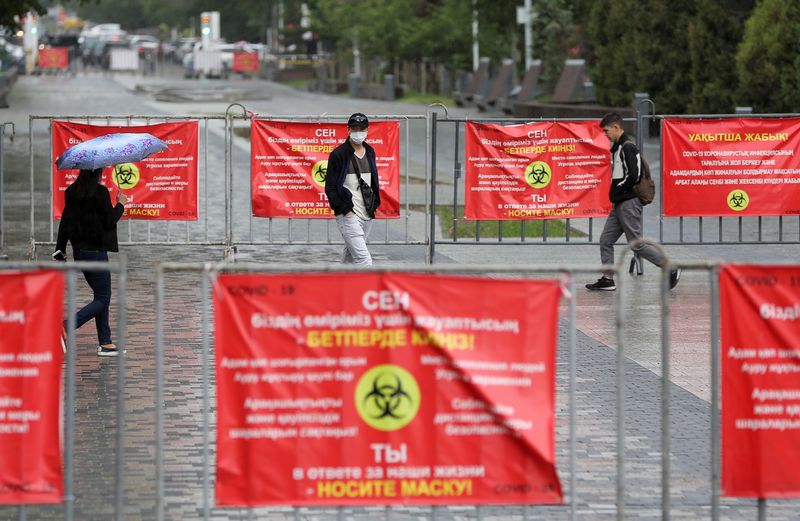 People walk past banners informing of preventive measures against the