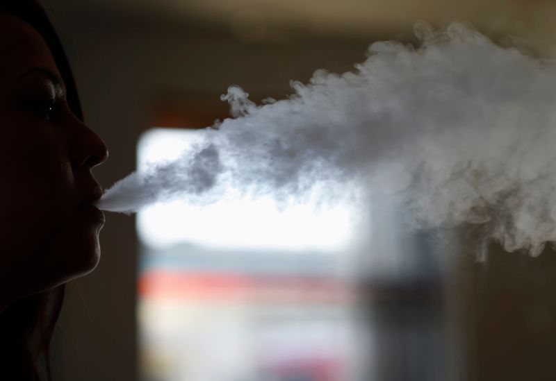 A woman exhales vapor from an electronic cigarette at a