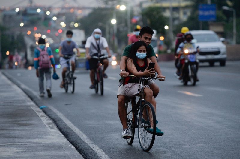 A cyclist carries a passenger in Manila