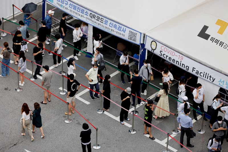 FILE PHOTO: People wait in line for a coronavirus disease