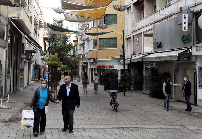 People wearing protective face masks walk in Ledra Street, a