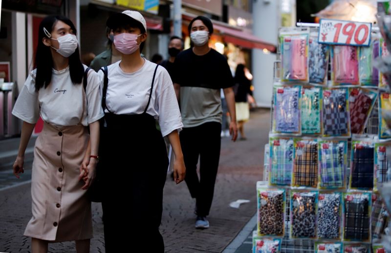 Women walk by a shop selling masks in Tokyo