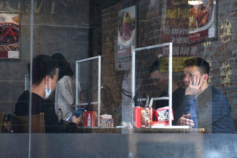 FILE PHOTO: People sit in a restaurant behind plastic dividers