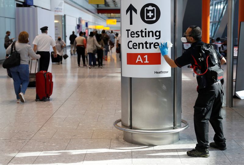 A worker sanitises a sign at the International arrivals area