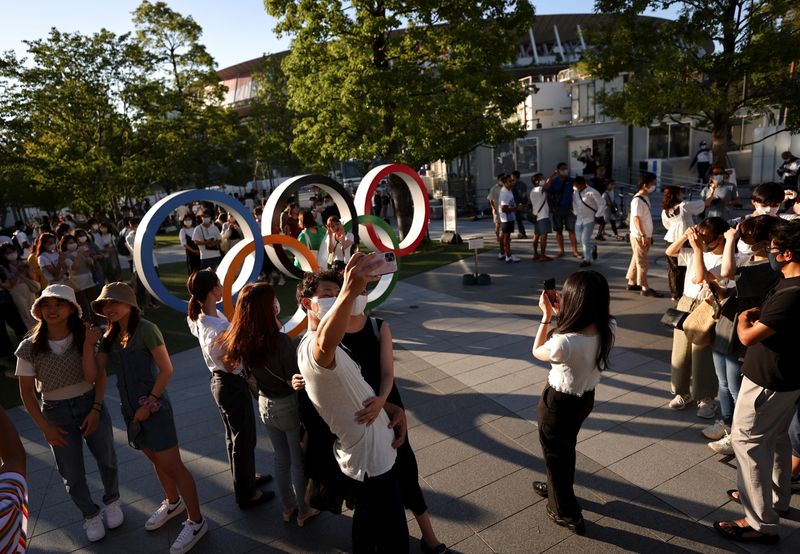 People take photos with an Olympic rings monument outside the