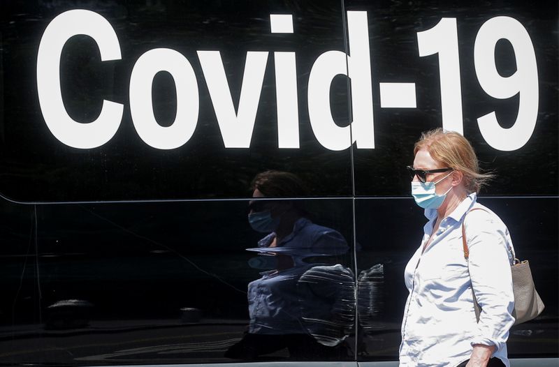 A woman passes by a COVID-19 mobile testing van in