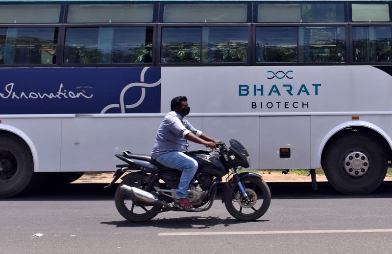 A man rides his motorbike past a parked bus of