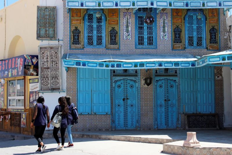 Girls walk past a closed souvenir shop in El Jem