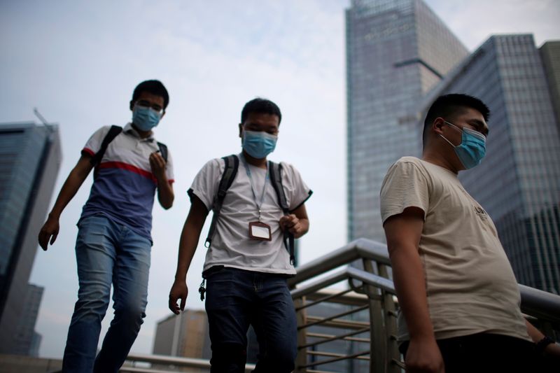 Men wearing protective masks walk on a bridge, following new