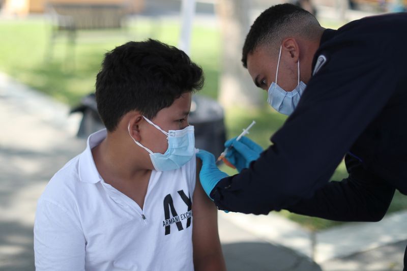 Alessandro Roque, 12, receives a coronavirus disease (COVID-19) vaccination as
