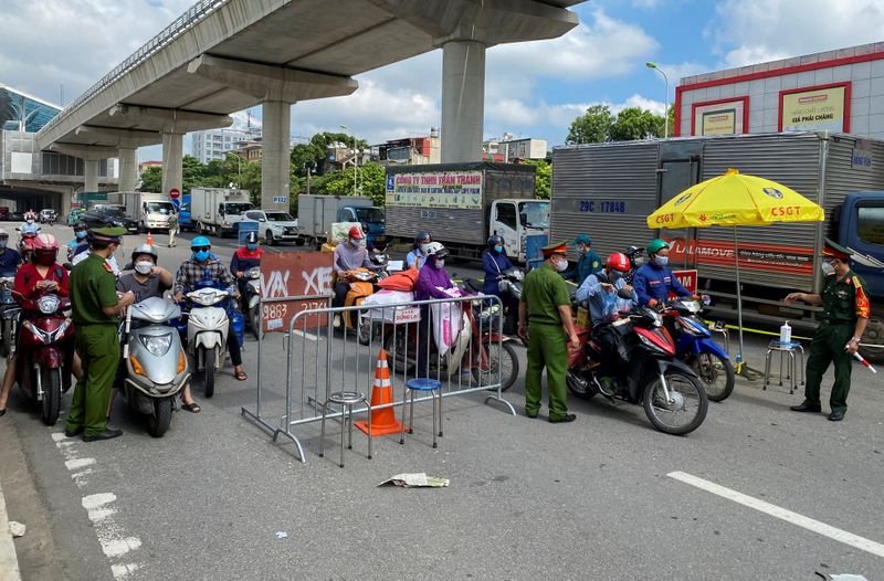 Vietnam police officers inspect commuters at a check point during