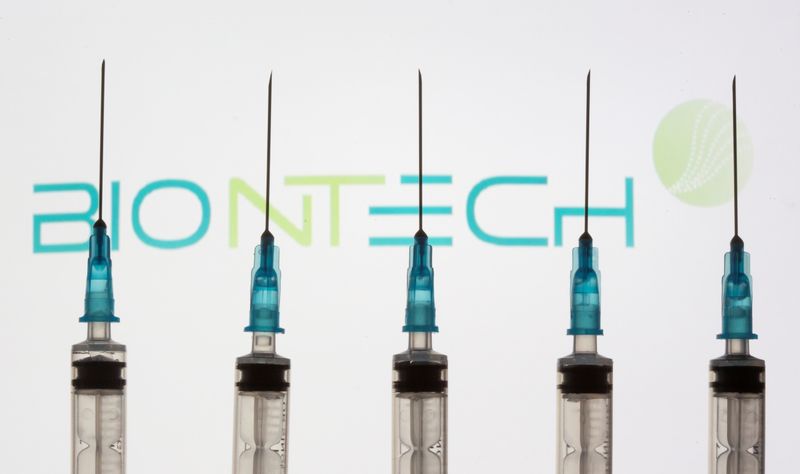 Syringes are seen in front of a displayed Biontech logo