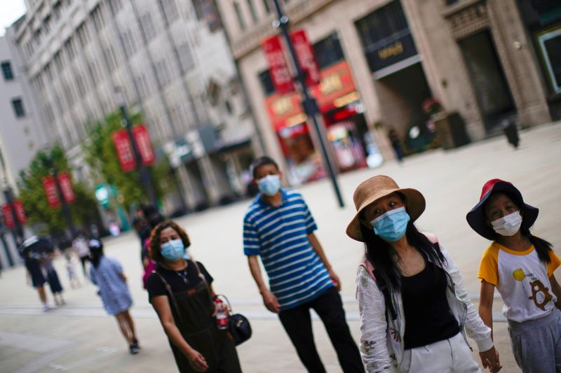 People wearing protective face masks walk on a street in