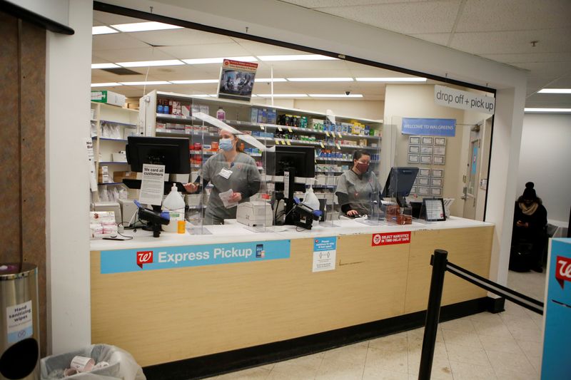 FILE PHOTO: People work behind a pharmacy counter as people