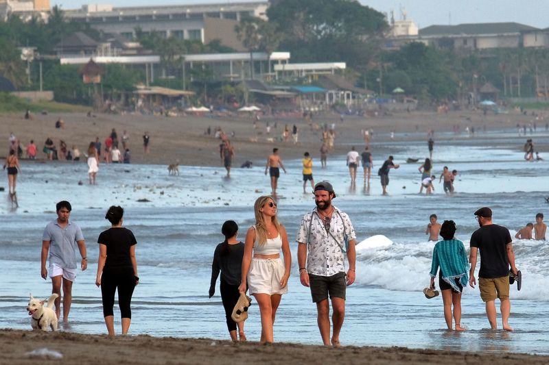 FILE PHOTO: Tourists walk on a beach as the government