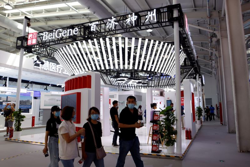 People walk past a booth of biotech company Beigene in
