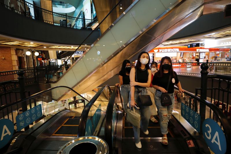 Visitors wearing protective masks walk at a shopping mall in
