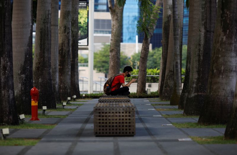 A man wearing a face mask sits outside a mall