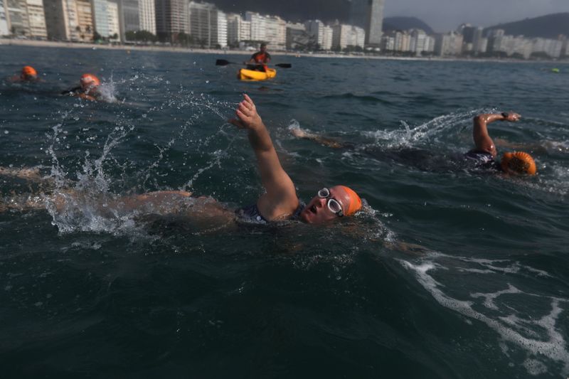 People warm out before swimming classes in Copacabana beach in