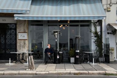 A man sits outside a closed cafe, amid the coronavirus