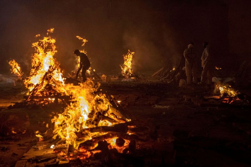 FILE PHOTO: People cremate the bodies of victims of the