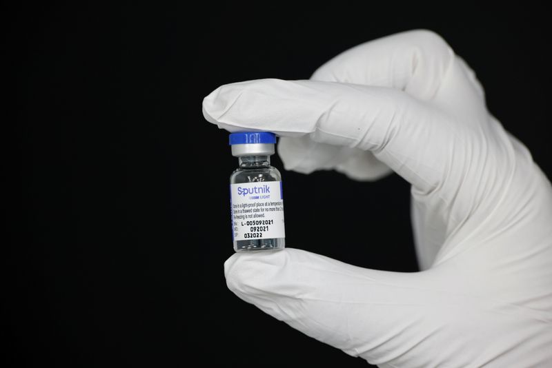 An employee holds a vial containing Sputnik vaccine at a