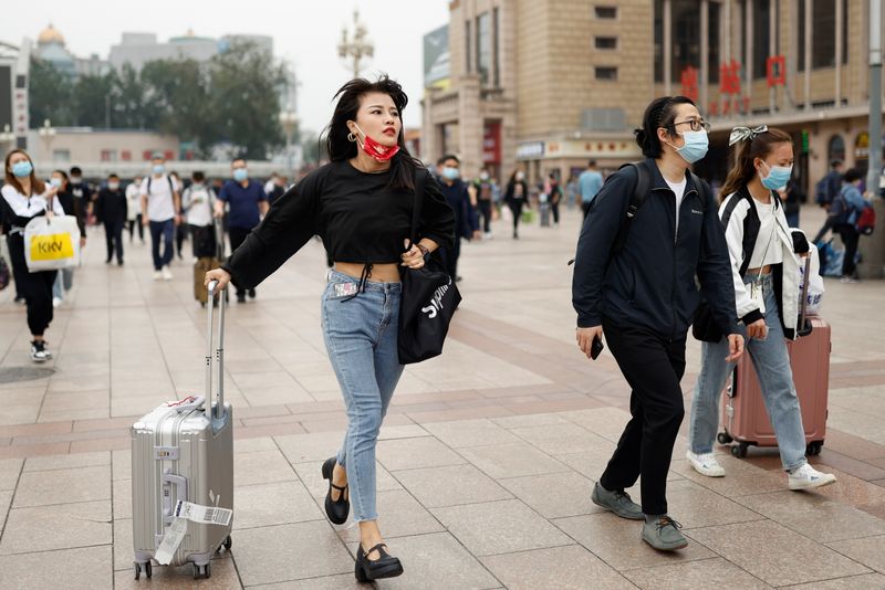 People walk with their luggage outside the Beijing Railway Station