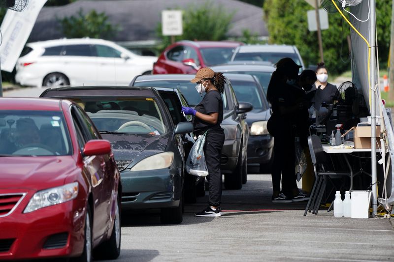 A woman assists a client as people in cars wait
