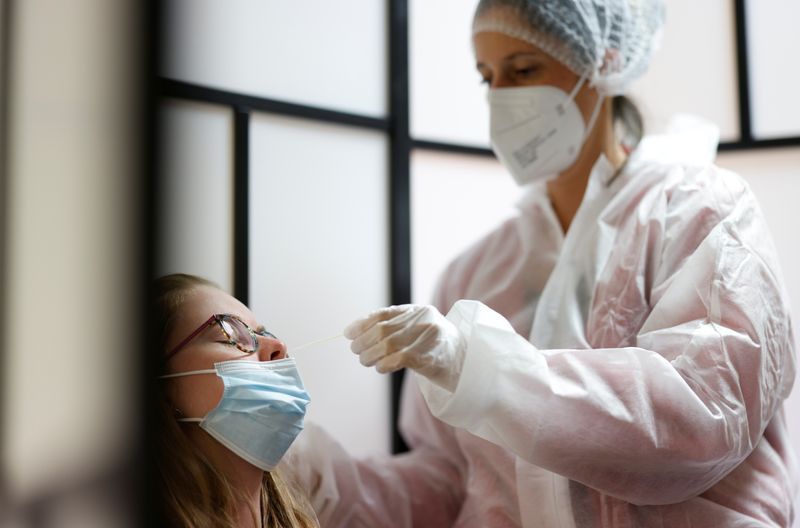A medical worker administers a nasal swab to a patient