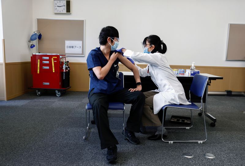 A medical worker receives a dose of the coronavirus disease