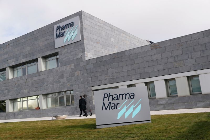 Workers walk outside the Spanish pharmaceutical company PharmaMar amid the