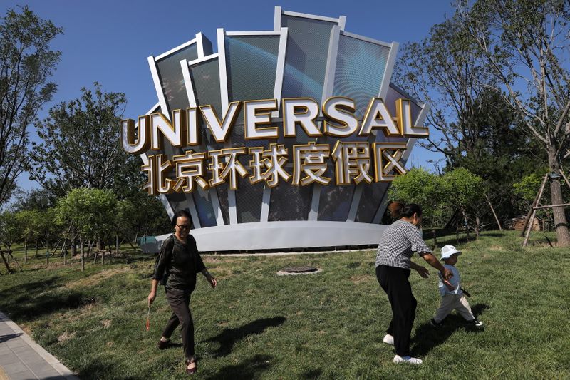 People walk past a giant sign of the Universal Beijing