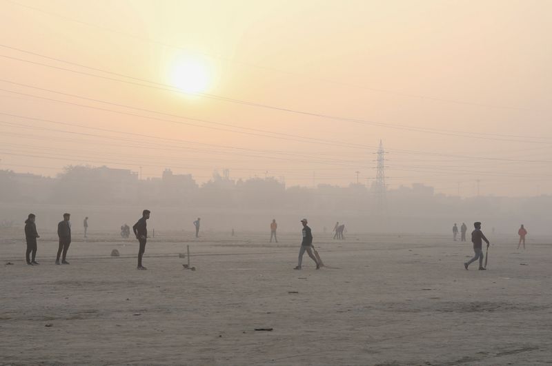 FILE PHOTO: People play cricket on the floodplains of the