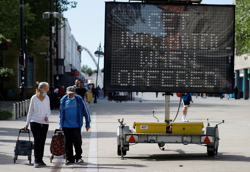 People pull shopping carts as they walk past an information