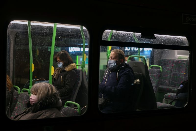 People wearing face masks sit on a bus in London