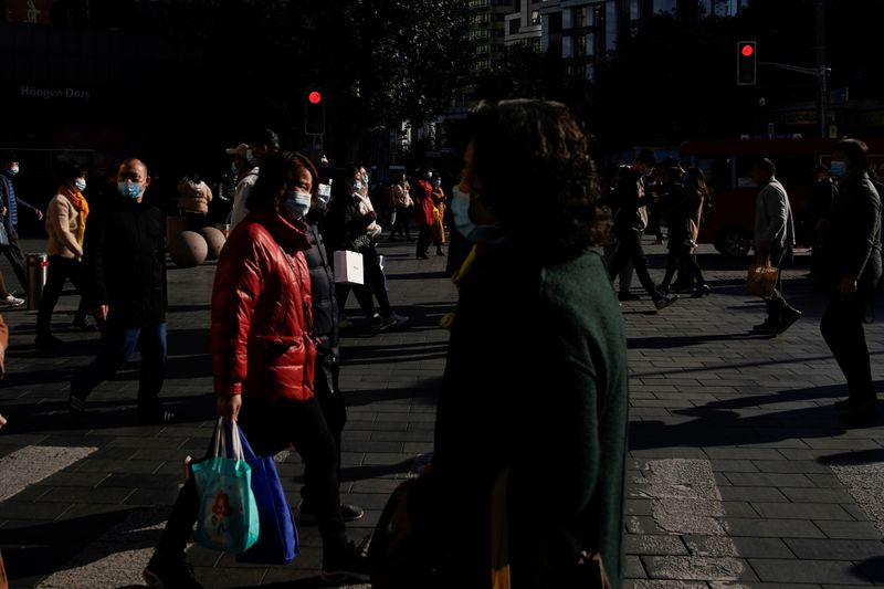 People wearing protective masks walk on a street, following new