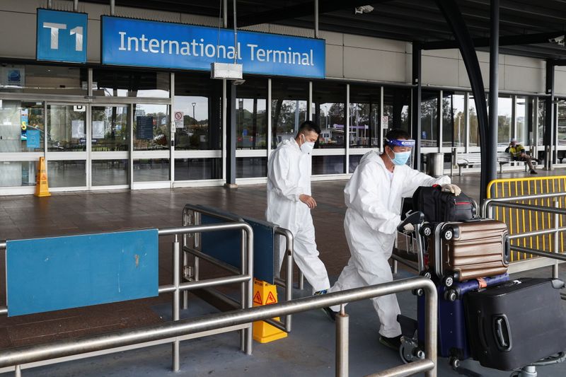 Travellers wear personal protective equipment outside the international terminal at