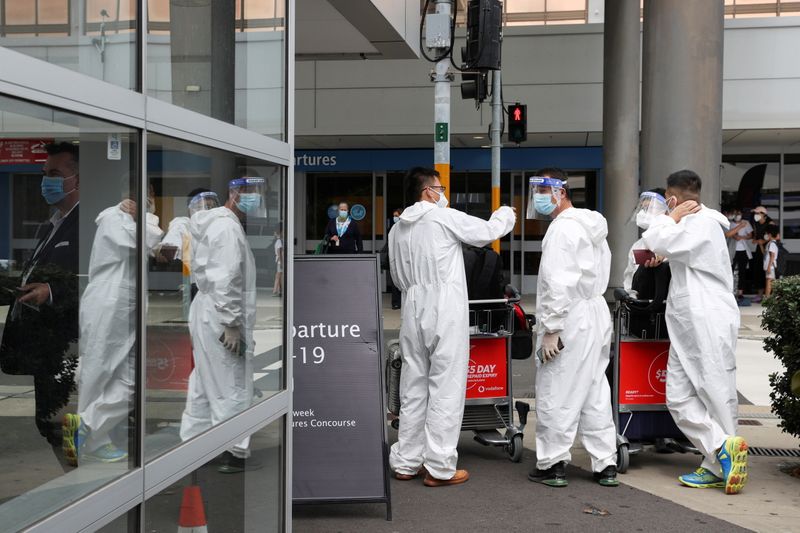 Travellers wear personal protective equipment outside the international terminal at