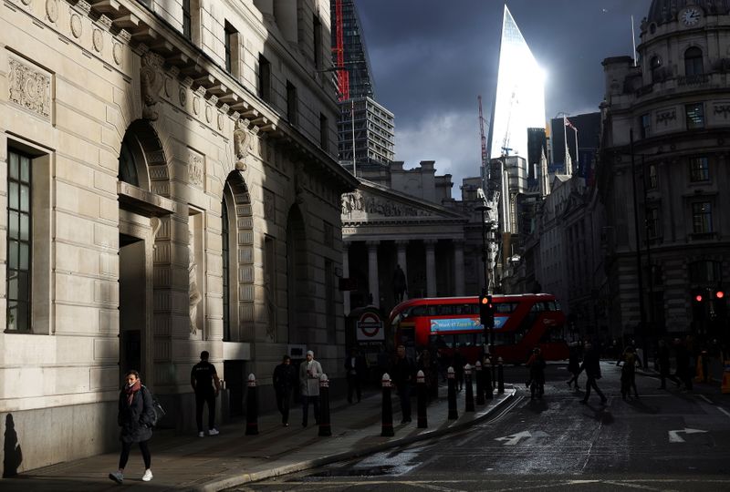 People walk through the City of London financial district, amid