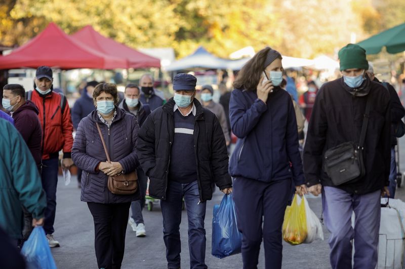 People wearing protective masks walk at market in Bucharest