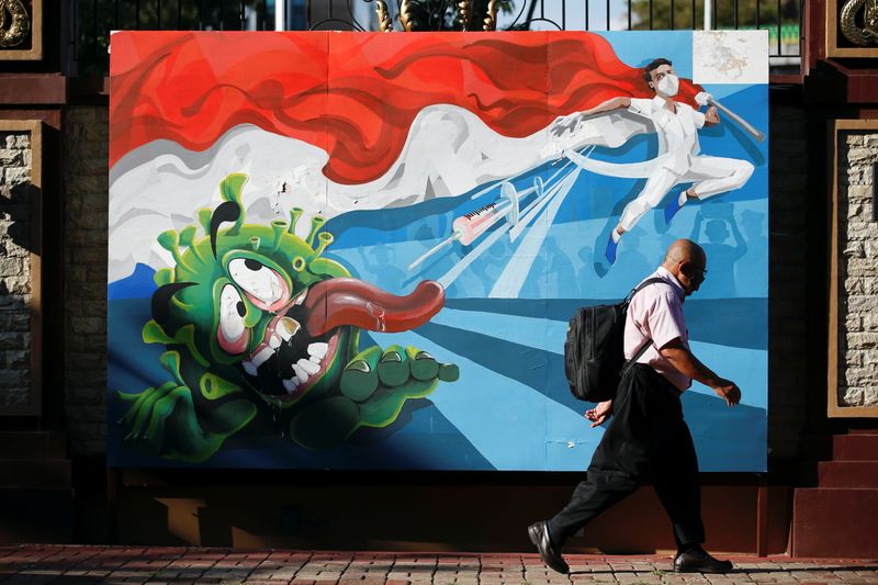 A man walks past a mural depicting a character attempting