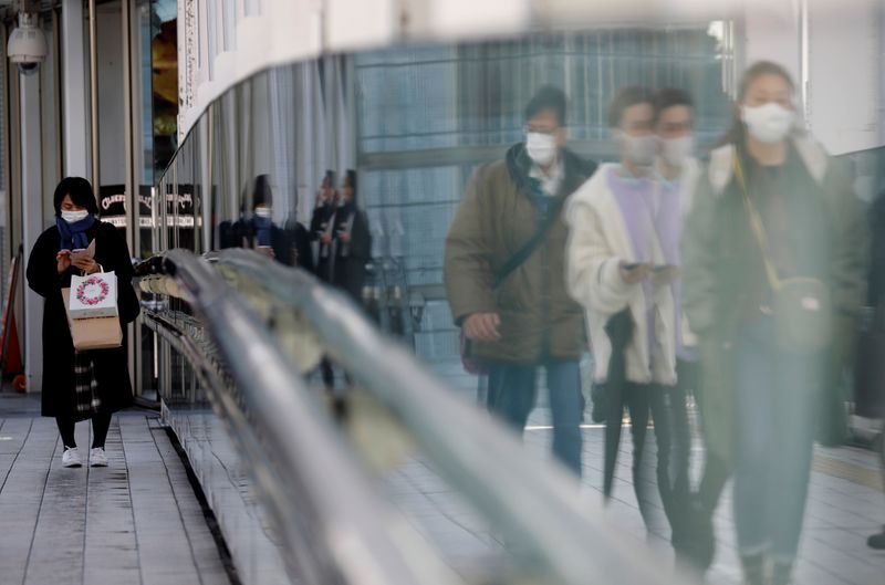 FILE PHOTO: Pedestrians wearing protective masks amid the coronavirus disease