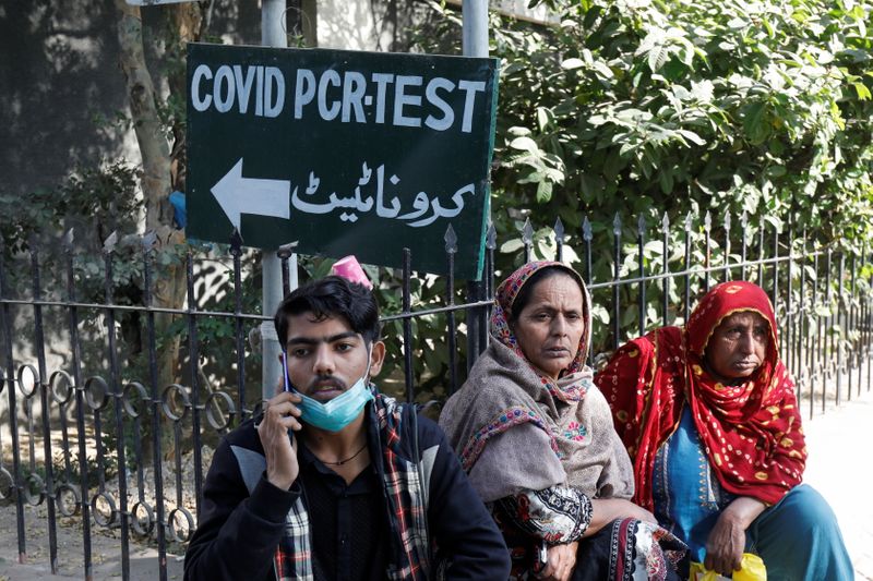 People sit next to a sign, for the coronavirus disease
