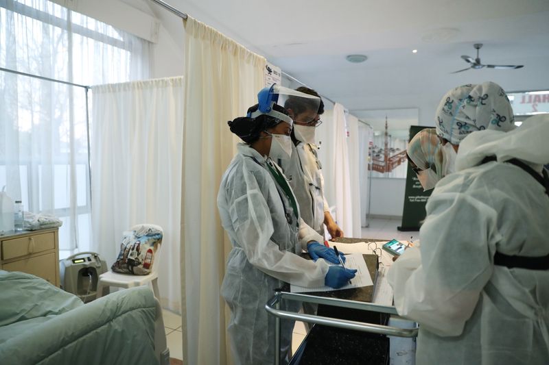 Healthcare workers assist patients being treated at a makeshift hospital